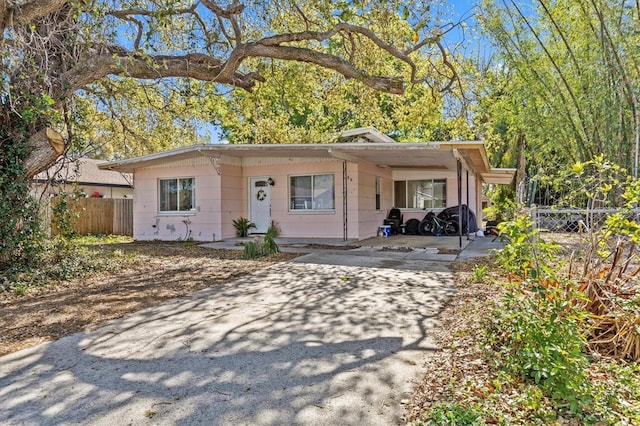 view of front of home featuring concrete driveway, a carport, and fence