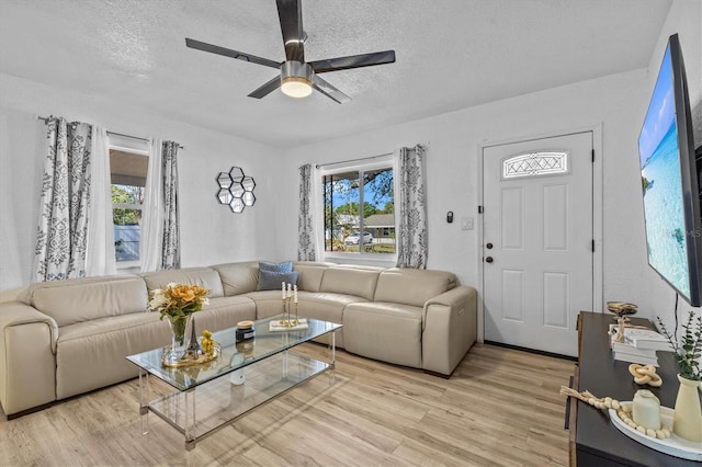 living area featuring a textured ceiling, a ceiling fan, and light wood finished floors