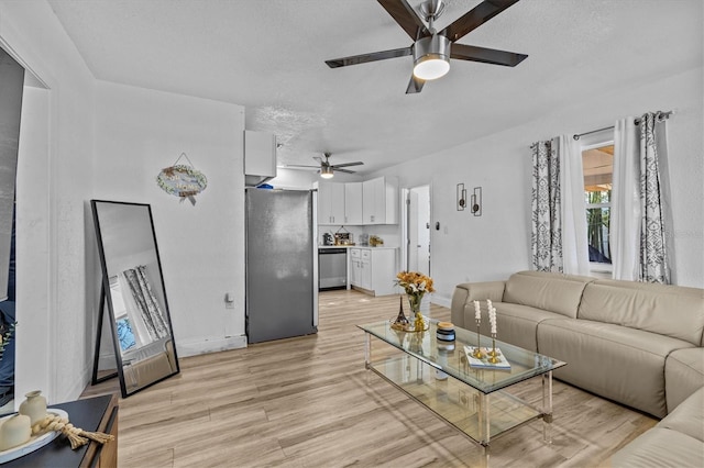 living room featuring light wood finished floors, a textured ceiling, and ceiling fan