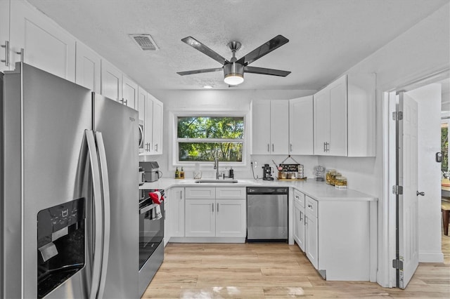 kitchen featuring visible vents, white cabinetry, stainless steel appliances, and a sink