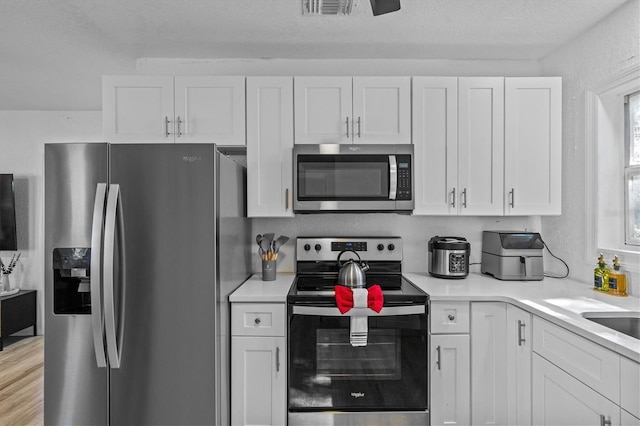 kitchen with visible vents, appliances with stainless steel finishes, light countertops, and white cabinetry