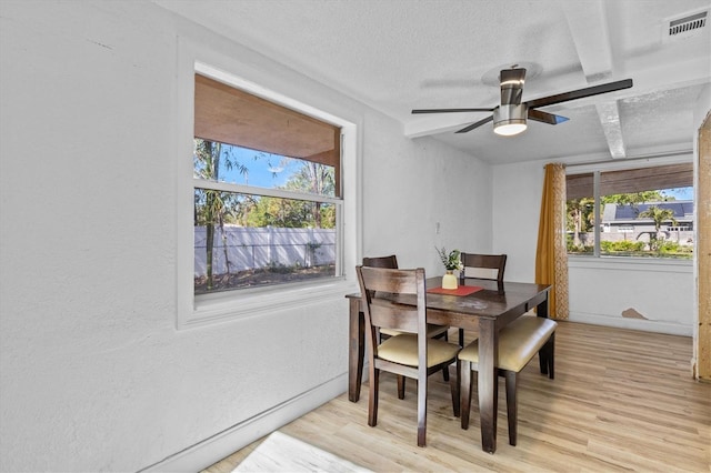 dining space with light wood finished floors, visible vents, a textured ceiling, and ceiling fan