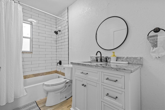 full bathroom with toilet, wood finished floors, a textured wall, vanity, and shower / bathtub combination with curtain