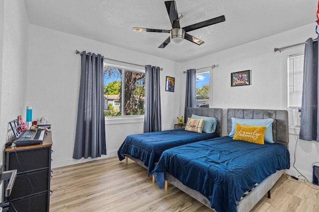 bedroom featuring light wood-style flooring, a textured ceiling, baseboards, and a ceiling fan