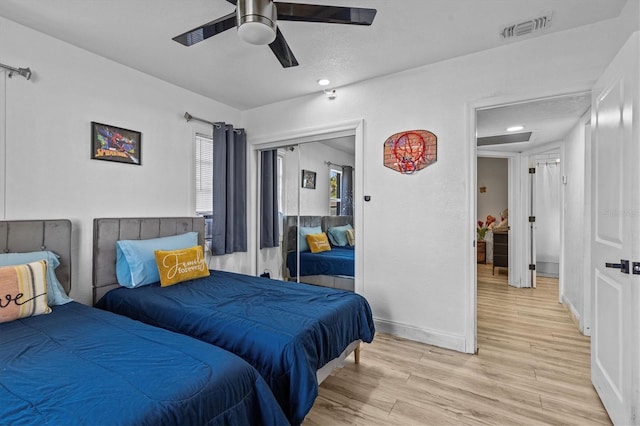 bedroom with visible vents, a ceiling fan, a closet, light wood-style floors, and baseboards