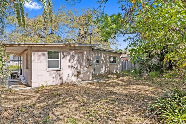 exterior space featuring concrete block siding and fence