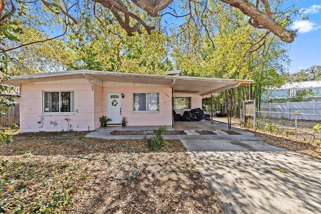 view of front facade with a carport, driveway, and fence