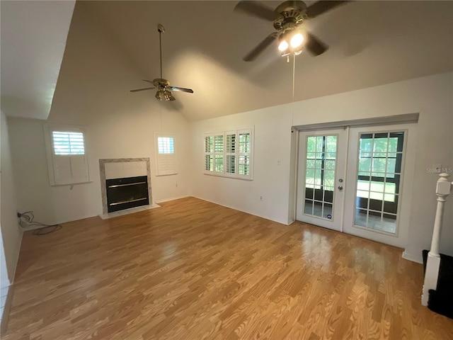 unfurnished living room featuring a ceiling fan, a high end fireplace, french doors, light wood-style floors, and lofted ceiling