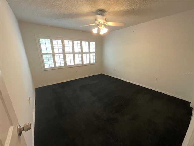 unfurnished room featuring a textured ceiling, baseboards, dark colored carpet, and ceiling fan