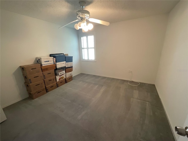 interior space with baseboards, dark carpet, a textured ceiling, and a ceiling fan