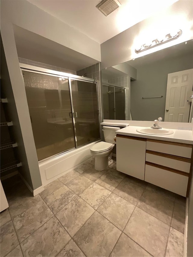 bathroom featuring visible vents, toilet, combined bath / shower with glass door, and vanity