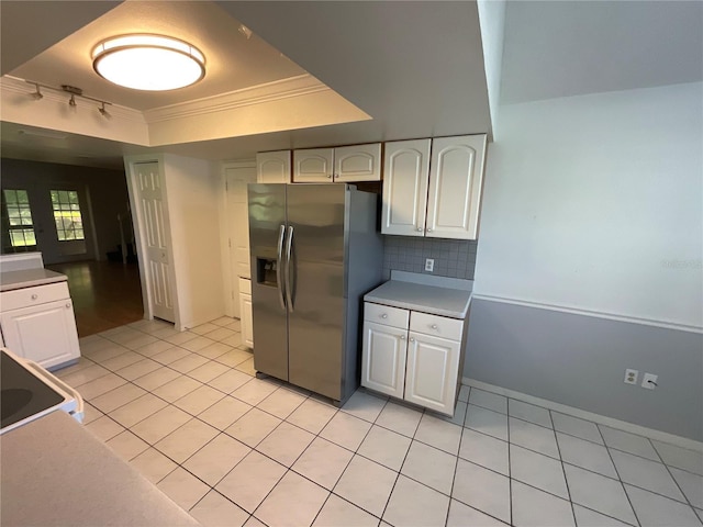 kitchen with ornamental molding, stainless steel refrigerator with ice dispenser, white cabinetry, a raised ceiling, and tasteful backsplash