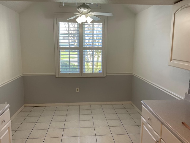 unfurnished dining area with light tile patterned floors, a healthy amount of sunlight, baseboards, and a ceiling fan