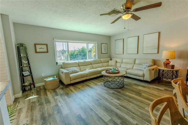 living area featuring baseboards, a textured ceiling, wood finished floors, and a ceiling fan