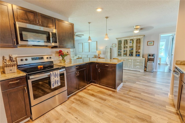 kitchen with a peninsula, light wood-style floors, a textured ceiling, stainless steel appliances, and a ceiling fan