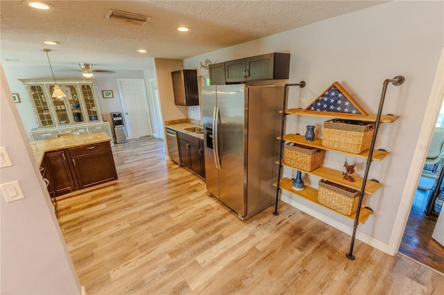 kitchen featuring light wood-type flooring, light countertops, stainless steel appliances, a textured ceiling, and a sink