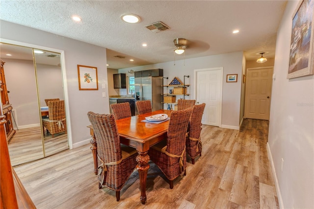 dining space with visible vents, baseboards, a textured ceiling, and light wood finished floors