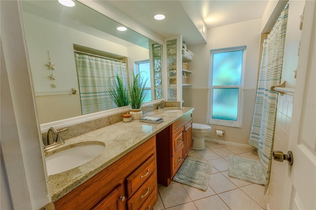 bathroom with tile patterned floors, toilet, double vanity, and a sink