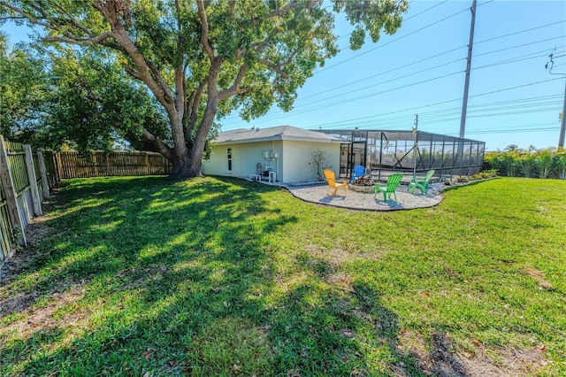 view of yard with a lanai, a fenced backyard, and an outdoor fire pit