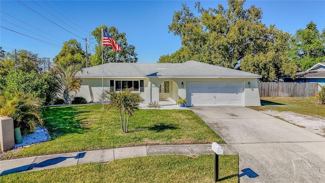 ranch-style home featuring a front lawn, fence, stucco siding, a garage, and driveway