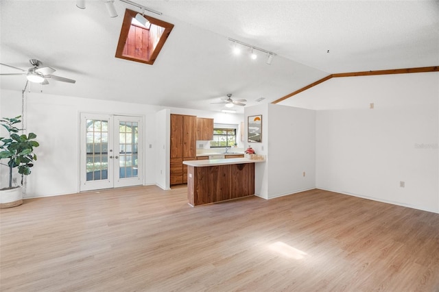 kitchen with a peninsula, a ceiling fan, open floor plan, and brown cabinets