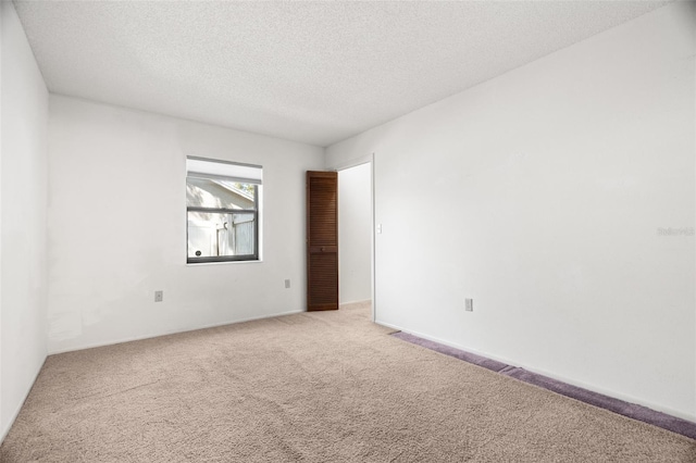 empty room with light colored carpet and a textured ceiling