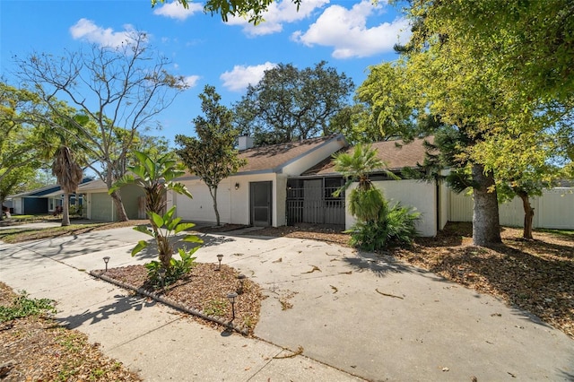 single story home with a chimney, concrete driveway, a garage, and fence