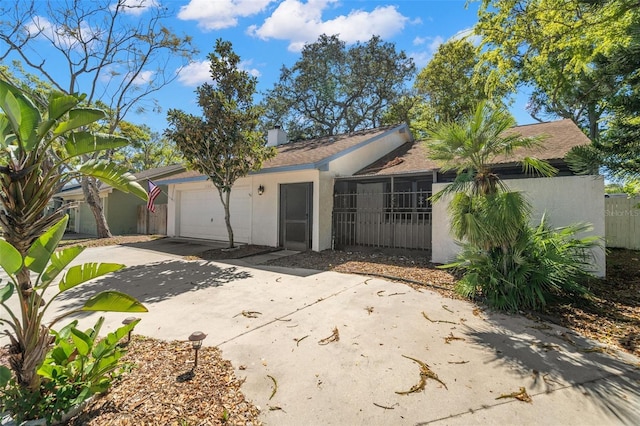 ranch-style home featuring stucco siding, fence, concrete driveway, an attached garage, and a chimney