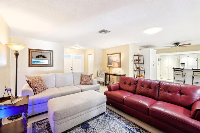 living area featuring a textured ceiling, visible vents, and ceiling fan