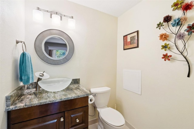 half bath featuring vanity, toilet, and baseboards