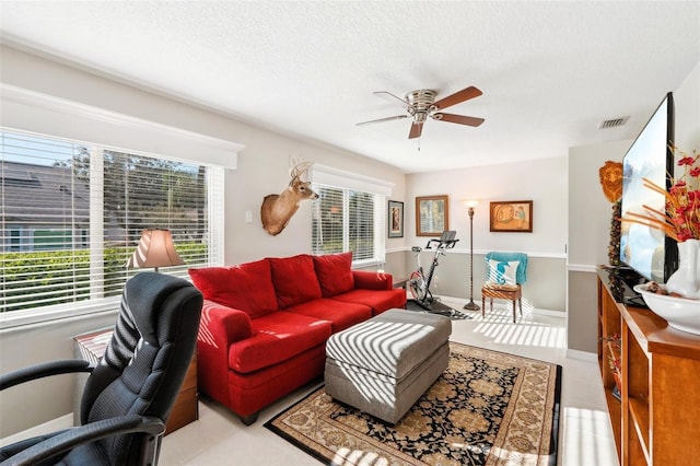 living room featuring baseboards, a ceiling fan, visible vents, and a textured ceiling