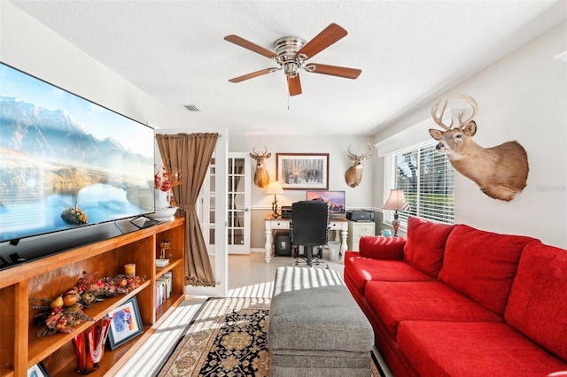 living area featuring visible vents, a textured ceiling, and ceiling fan