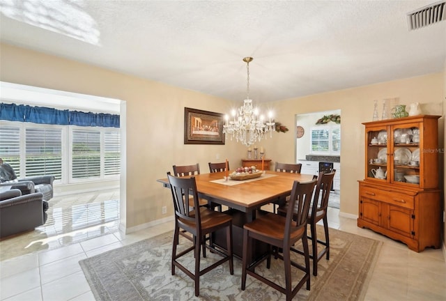 dining area featuring a notable chandelier, visible vents, baseboards, and light tile patterned floors