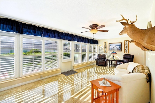 living area featuring baseboards and ceiling fan