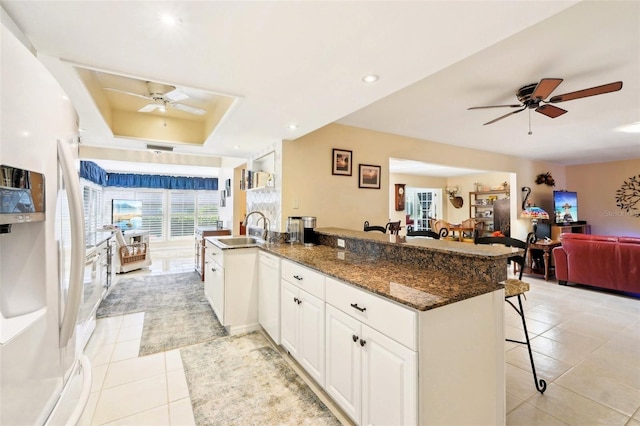 kitchen with ceiling fan, open floor plan, a breakfast bar, freestanding refrigerator, and a sink