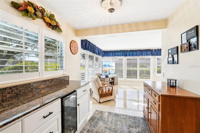 living area with beverage cooler, light tile patterned floors, a healthy amount of sunlight, and a textured ceiling