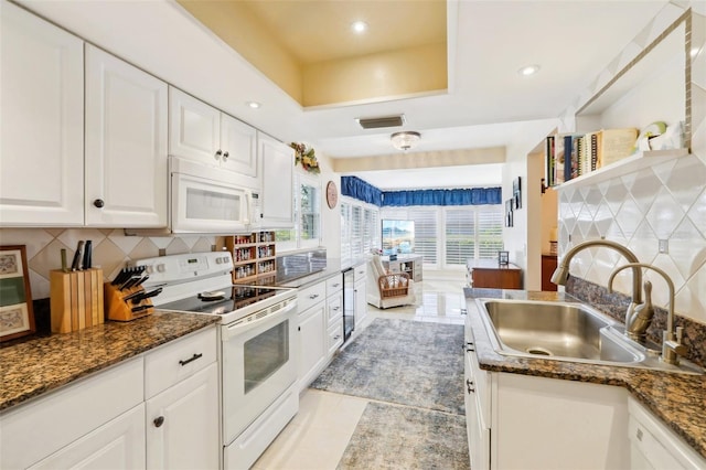 kitchen featuring white appliances, visible vents, a tray ceiling, a sink, and white cabinetry