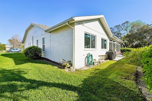 view of side of property featuring stucco siding and a lawn