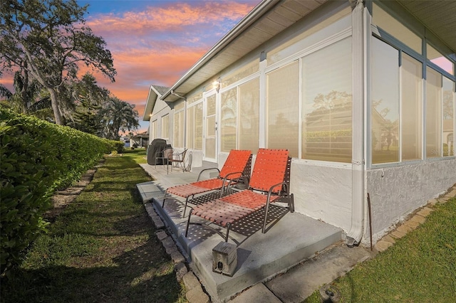 property exterior at dusk featuring stucco siding and a patio