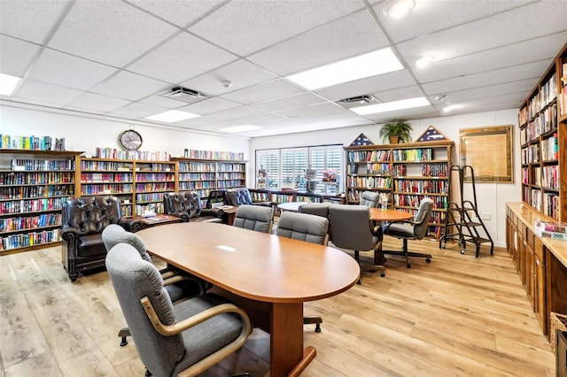 office area with bookshelves, a paneled ceiling, and wood finished floors