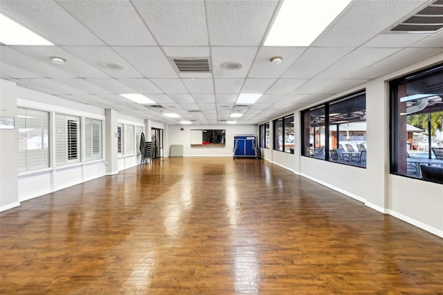 interior space with wood finished floors, visible vents, a drop ceiling, and baseboards