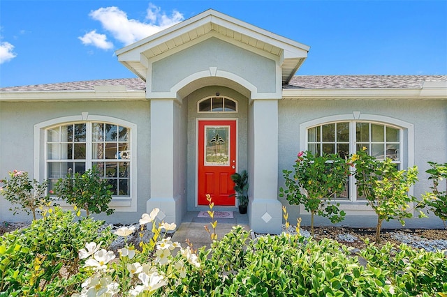 property entrance with a shingled roof and stucco siding