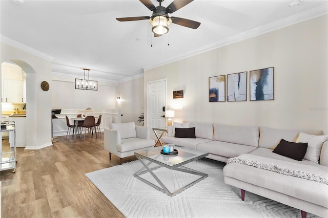 living area with arched walkways, light wood-style flooring, a ceiling fan, and ornamental molding