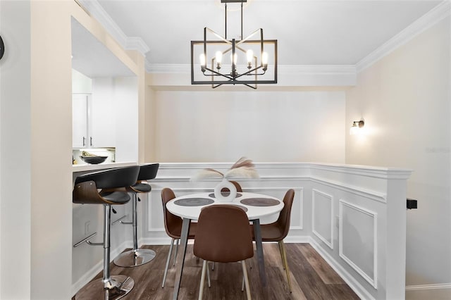 dining room featuring wainscoting, dark wood-style flooring, crown molding, and a decorative wall