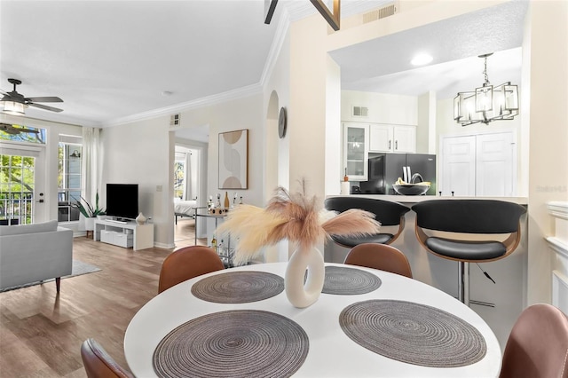 dining space featuring a wealth of natural light, visible vents, wood finished floors, and ornamental molding