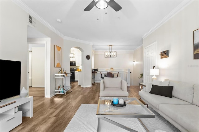 living room with visible vents, wood finished floors, arched walkways, and ornamental molding