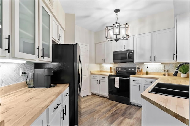 kitchen with black appliances, a sink, glass insert cabinets, white cabinets, and decorative backsplash