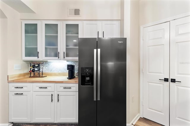 kitchen featuring white cabinets, stainless steel fridge with ice dispenser, visible vents, and wood counters