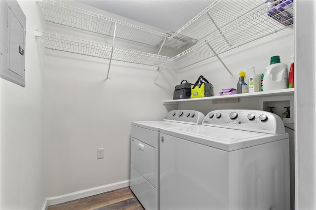 clothes washing area with electric panel, laundry area, baseboards, dark wood-style flooring, and washing machine and clothes dryer