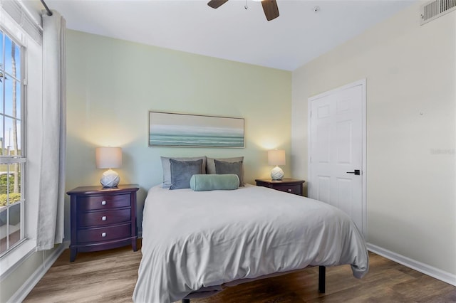 bedroom with visible vents, ceiling fan, baseboards, and wood finished floors